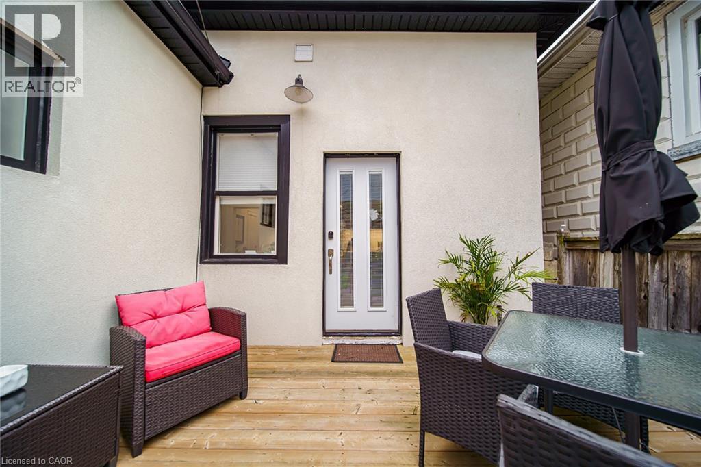 Outdoor wood-finish decking with an exterior light fixture and a white paneled door - 28 Cambridge Street, Cambridge, ON