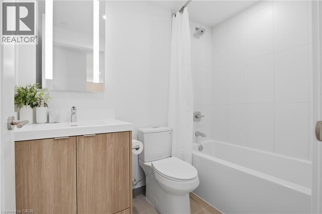 Modern bathroom featuring a wood-finish vanity with a white countertop, illuminated mirror, and a tiled shower/tub combination - 60 Central Park Roadway Unit# 2010, Etobicoke, ON