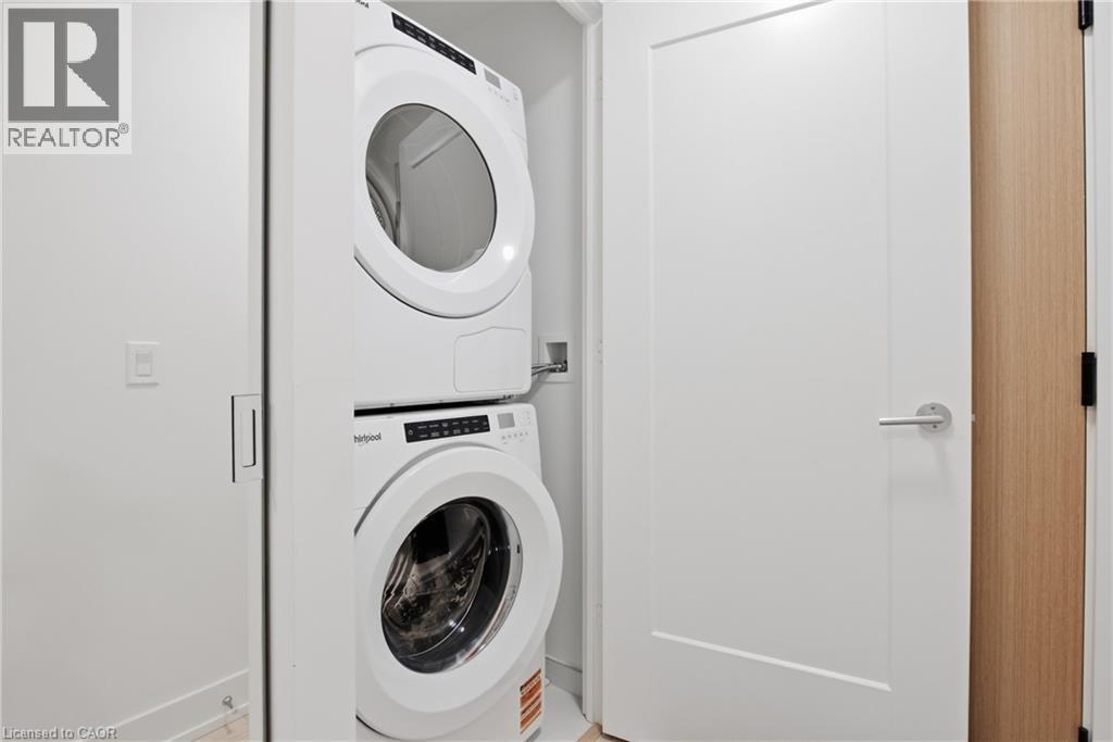 Stacked washer and dryer unit, white flat panel door with brushed nickel hardware, and wood-finish door casing - 60 Central Park Roadway Unit# 2010, Etobicoke, ON