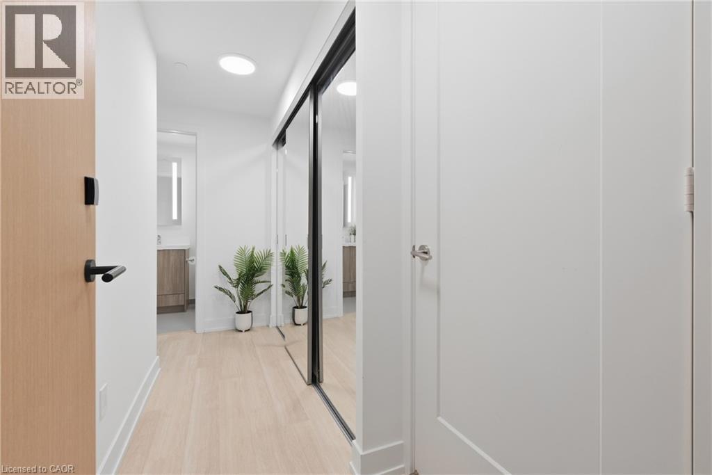Light wood-finish flooring with recessed ceiling lighting, a full-height mirrored sliding closet door, and a light wood-finish entry door with black hardware - 60 Central Park Roadway Unit# 2010, Etobicoke, ON