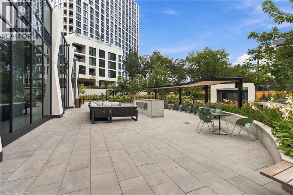 Expansive outdoor patio with large format pavers and curved planter beds, featuring an integrated pergola and modern exterior lighting - 60 Central Park Roadway Unit# 2010, Etobicoke, ON