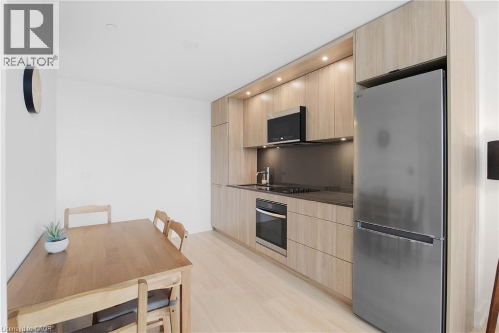 Compact kitchen featuring wood-finish cabinetry, stainless steel appliances, recessed lighting, and light wood-finish flooring - 60 Central Park Roadway Unit# 2010, Etobicoke, ON