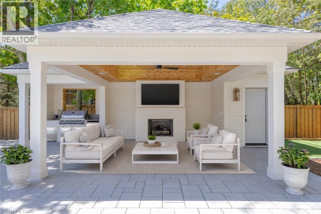 Covered outdoor living space featuring a brick fireplace, wood-finish ceiling, built-in outdoor kitchen, and a ceiling fan - 130 Edgecliffe Place, Halton, ON