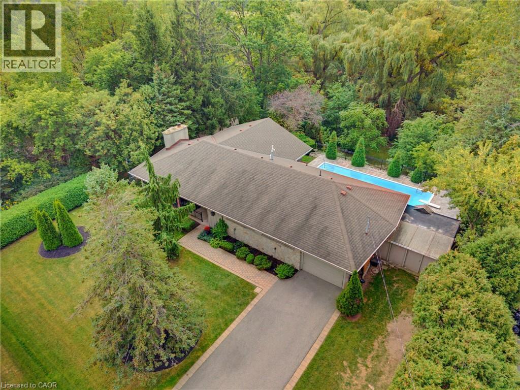 Expansive property featuring a paved driveway, mature trees, a manicured lawn, and an in-ground swimming pool - 1316 Nevarc Drive, Burlington, ON