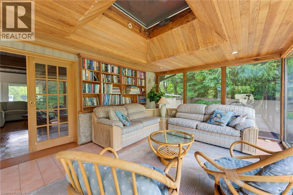 Wood-paneled ceiling with skylight, extensive built-in shelving, full-height window wall, French doors, and tile flooring - 1316 Nevarc Drive, Burlington, ON