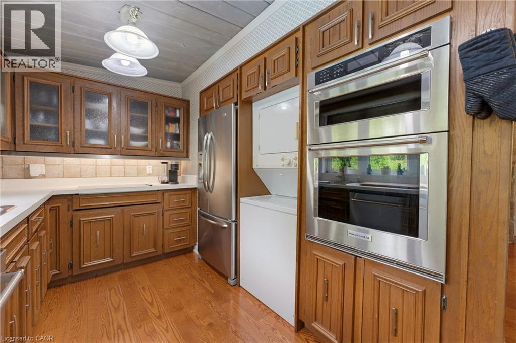Kitchen featuring wood-finish flooring, white countertops, tile backsplash, and stainless steel appliances including a built-in double oven and refrigerator - 1316 Nevarc Drive, Burlington, ON