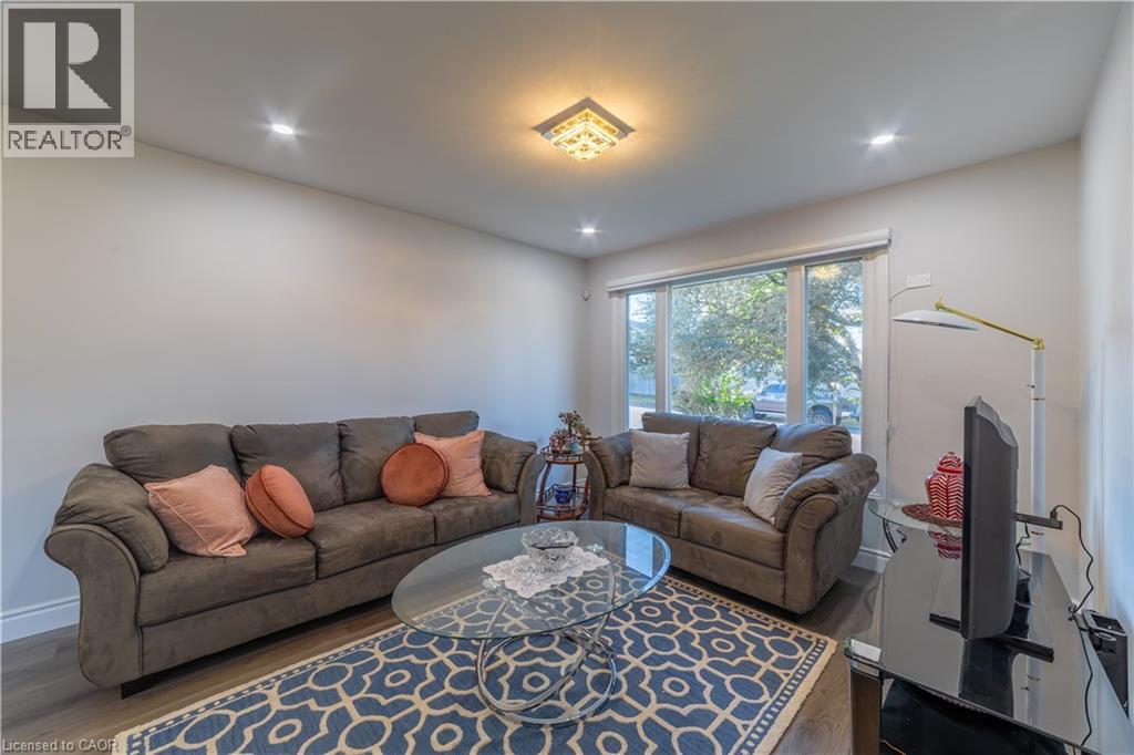 Recessed ceiling lighting, a central decorative ceiling light fixture, wood-finish flooring, and a large window - 137 Nickolas Crescent, Cambridge, ON