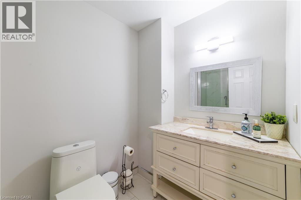 Corner vanity with integrated sink, stone countertop, and decorative mirror - 137 Nickolas Crescent, Cambridge, ON