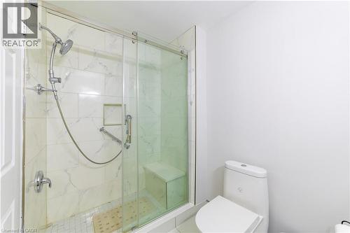 Shower with sliding glass enclosure, white tiled walls, built-in bench, and a modern toilet - 137 Nickolas Crescent, Cambridge, ON 
