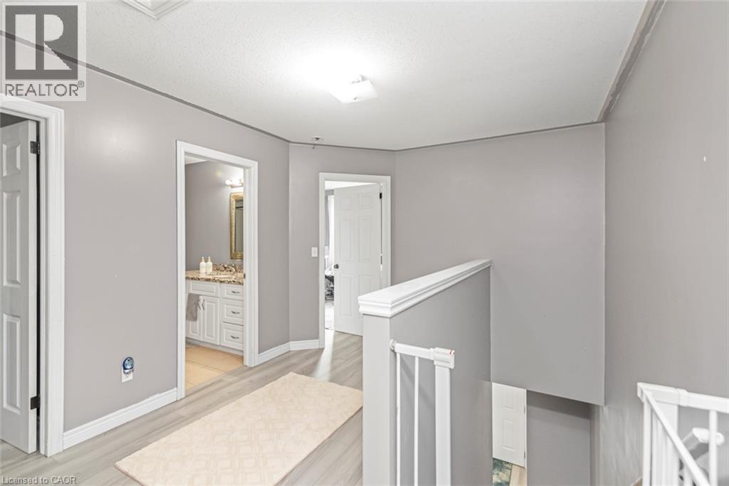Hallway with wood-finish flooring, white doors, and a bathroom vanity featuring a light-toned countertop - 42 Saturn Road, Port Colborne, ON