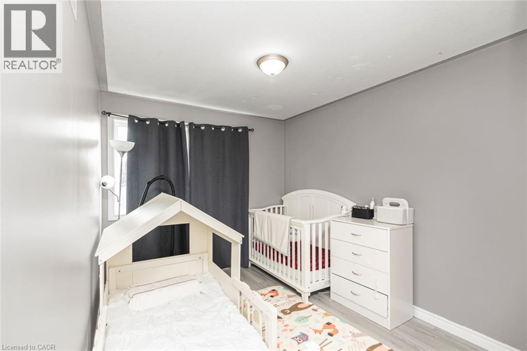 Light gray walls, recessed ceiling light, window with dark curtains, and light wood-finish flooring - 42 Saturn Road, Port Colborne, ON