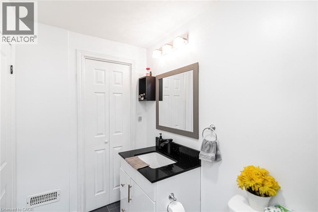 Vanity with black countertop and integrated sink, wall-mounted mirror, and bi-fold doors - 42 Saturn Road, Port Colborne, ON