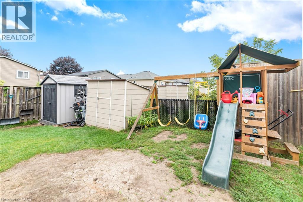 Expansive backyard featuring a partial grass lawn, two storage sheds, and a wooden fence - 42 Saturn Road, Port Colborne, ON