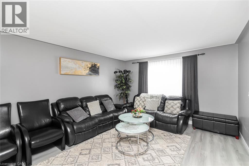Light grey walls with white trim, a large window with dark grey drapes, and wood-finish flooring - 42 Saturn Road, Port Colborne, ON