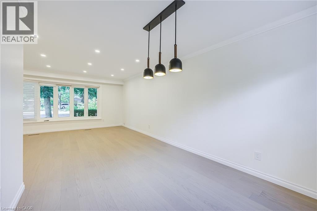 Recessed ceiling lighting, wood-finish flooring, crisp white walls, crown molding, and a modern linear pendant light fixture - 3148 Terraview Court, Burlington, ON