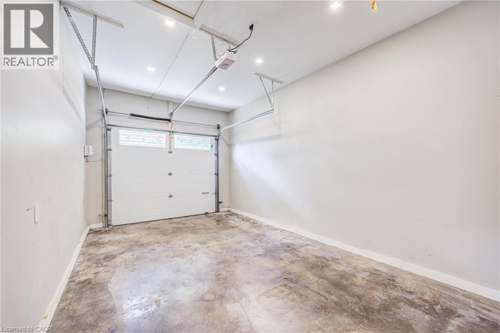 Concrete flooring, white walls, overhead garage door system, recessed lighting, and a white garage door with windows - 3148 Terraview Court, Burlington, ON