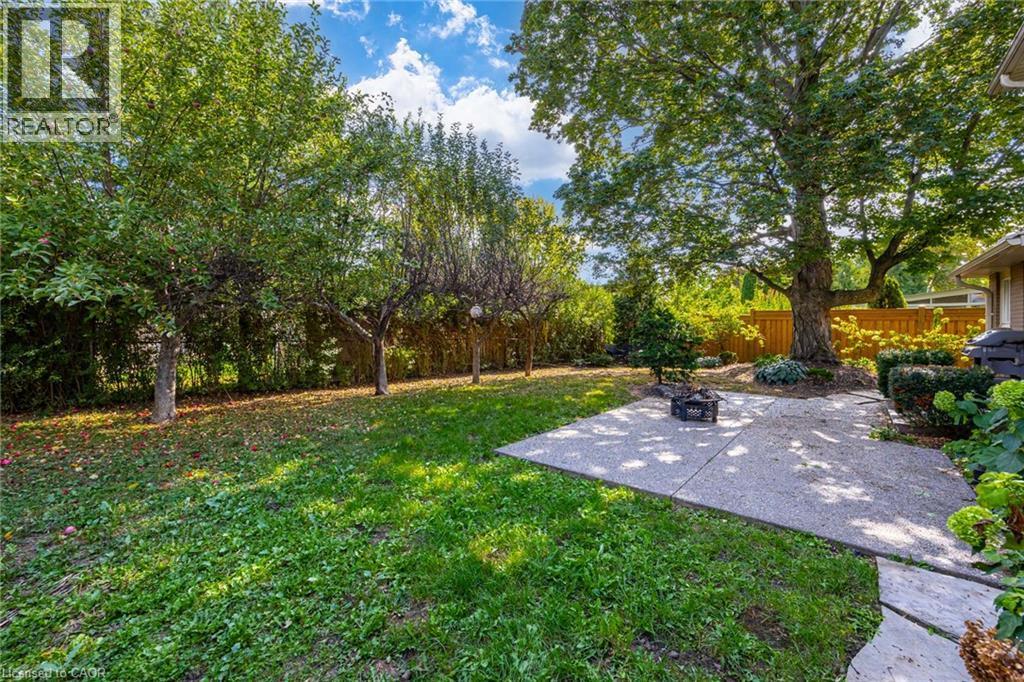 Expansive backyard with a concrete patio, mature trees, and natural landscaping - 3148 Terraview Court, Burlington, ON
