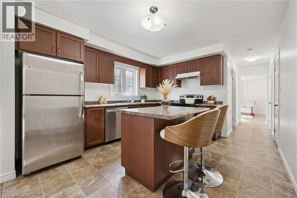 Full kitchen featuring wood-finish cabinetry, stainless steel appliances, stone-finish countertops, and a kitchen island with seating - 931 Glasgow Street Unit# 27B, Kitchener, ON