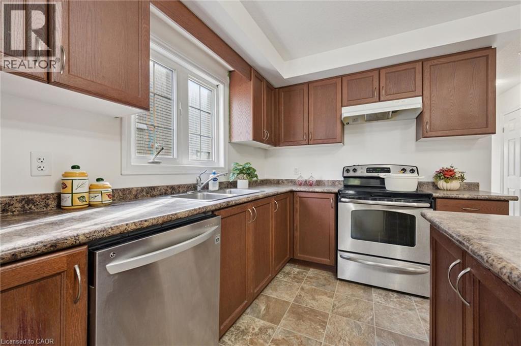 Kitchen featuring wood-finish cabinetry, stainless steel dishwasher, stainless steel range, and a window with blinds - 931 Glasgow Street Unit# 27B, Kitchener, ON