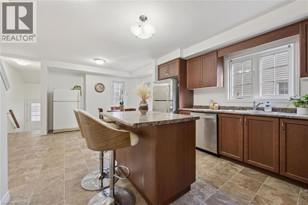 Kitchen featuring wood cabinetry, stainless steel appliances, a center island with seating, and tile flooring - 931 Glasgow Street Unit# 27B, Kitchener, ON