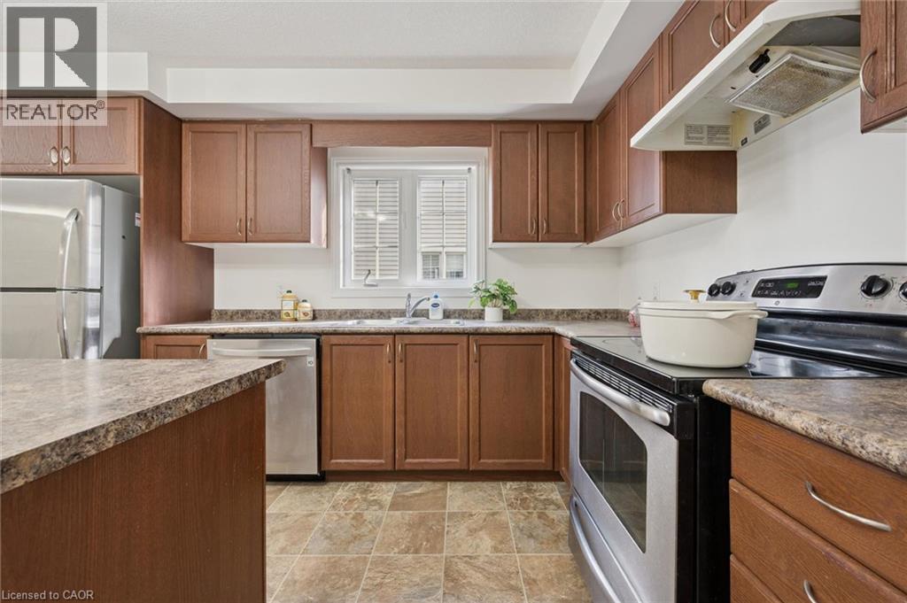 U-shaped kitchen with wood-finish cabinetry, tile flooring, stainless steel appliances, and a window with white louvered blinds - 931 Glasgow Street Unit# 27B, Kitchener, ON