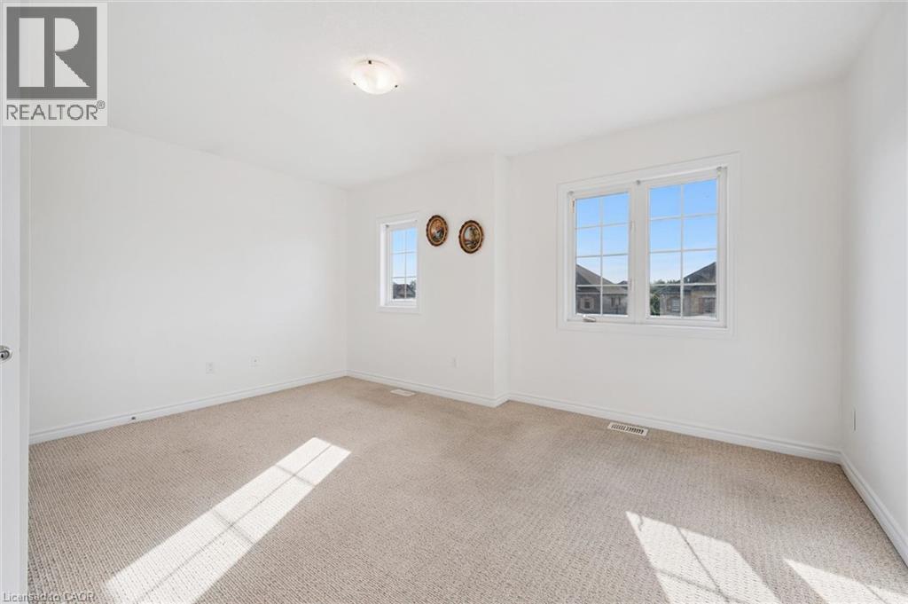 Spacious room featuring neutral carpeting, white walls, and multiple windows - 931 Glasgow Street Unit# 27B, Kitchener, ON
