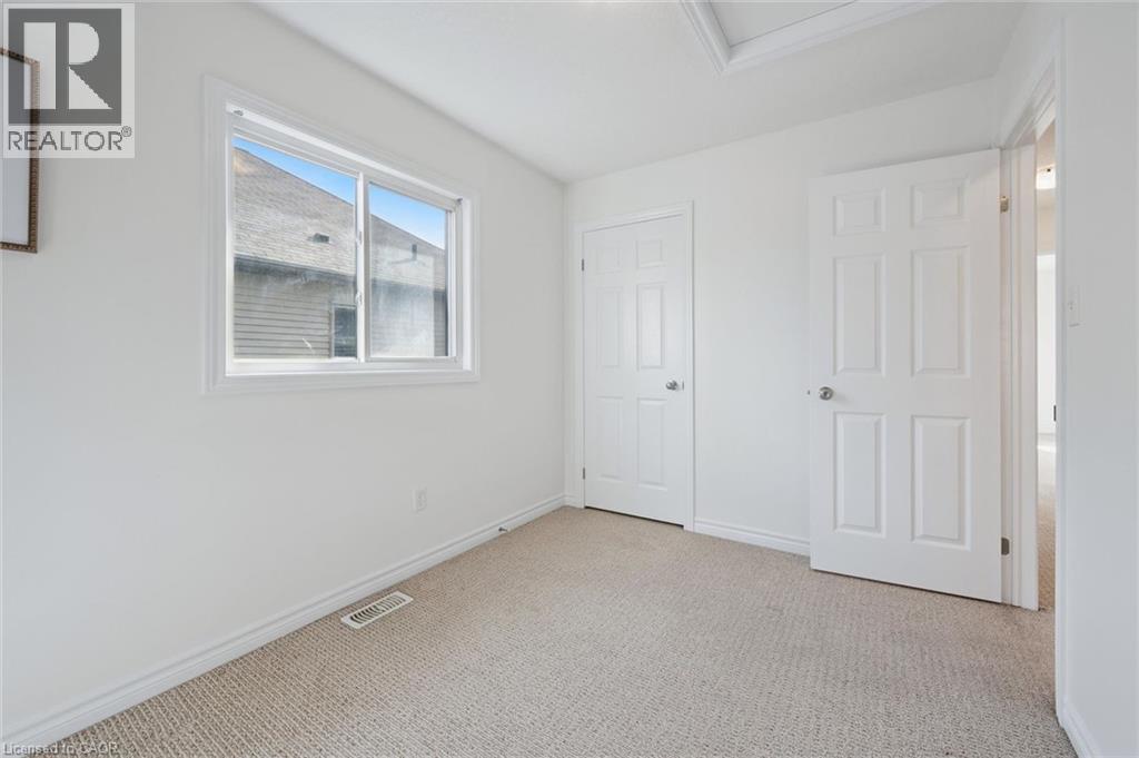 Carpeted room with a white framed window, two panel doors, and a ceiling hatch - 931 Glasgow Street Unit# 27B, Kitchener, ON