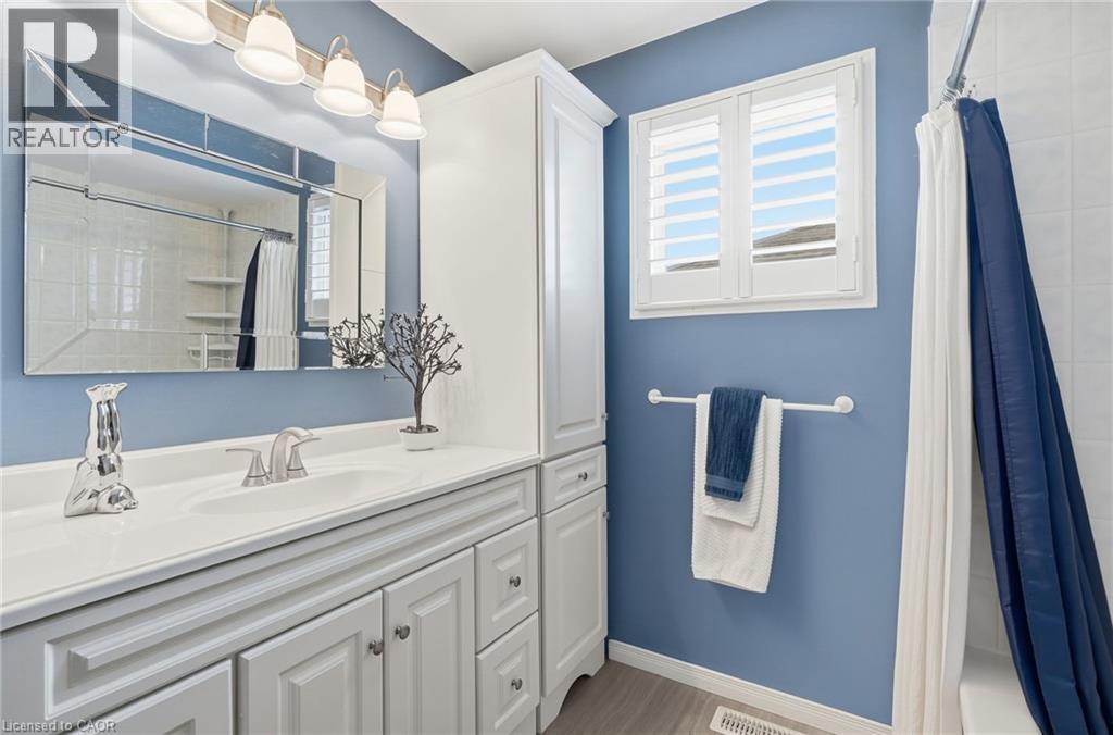White vanity with integrated sink, polished chrome faucet, and mirrored light fixture - 94 Kent Road, Brantford, ON