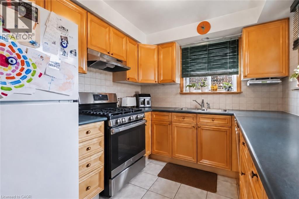Kitchen featuring wood-finish cabinetry, stainless steel range, and dual basin sink - 152 Hilda Avenue, North York, ON