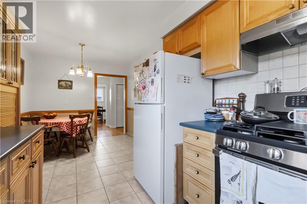 Kitchen featuring wood-finish cabinetry, tile flooring, and a stainless steel gas range with a coordinating range hood - 152 Hilda Avenue, North York, ON