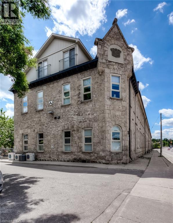 Stone facade architecture with a gabled dormer and balcony - 25 Concession Street Unit# 110, Cambridge, ON