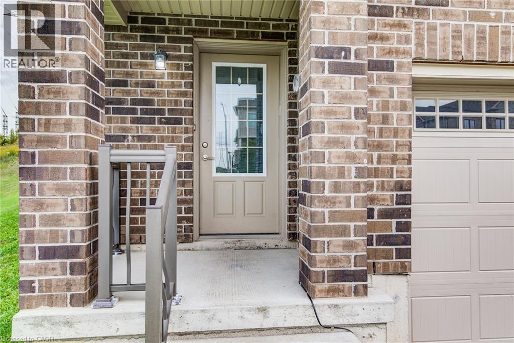 Brick exterior with a concrete front entry, modern metal handrail, and an attached garage with panel detailing - 226 Maitland Street, Kitchener, ON