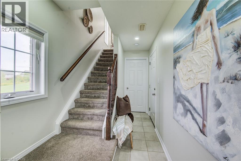 Carpeted staircase with wooden handrail, tile flooring, and a multi-pane window - 226 Maitland Street, Kitchener, ON