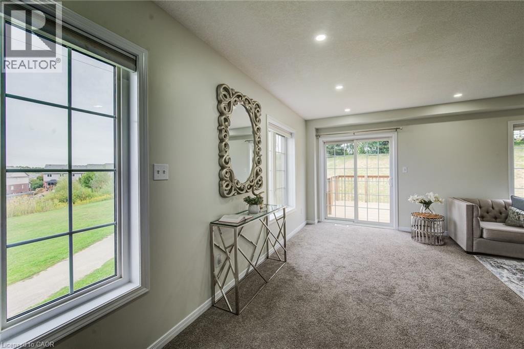 Spacious room featuring neutral carpeting, recessed lighting, and a sliding glass door opening to an outdoor deck - 226 Maitland Street, Kitchener, ON