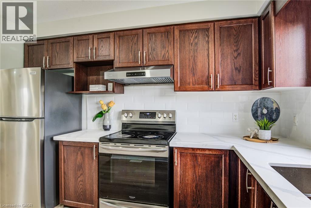 Stainless steel appliances, wood-finish cabinetry, white subway tile backsplash, and light-colored countertops - 226 Maitland Street, Kitchener, ON