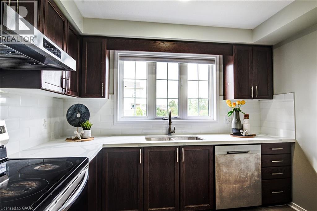 Dark wood-finish cabinetry, white subway tile backsplash, white countertops, stainless steel sink with a gooseneck faucet, and a large window with grid panes - 226 Maitland Street, Kitchener, ON