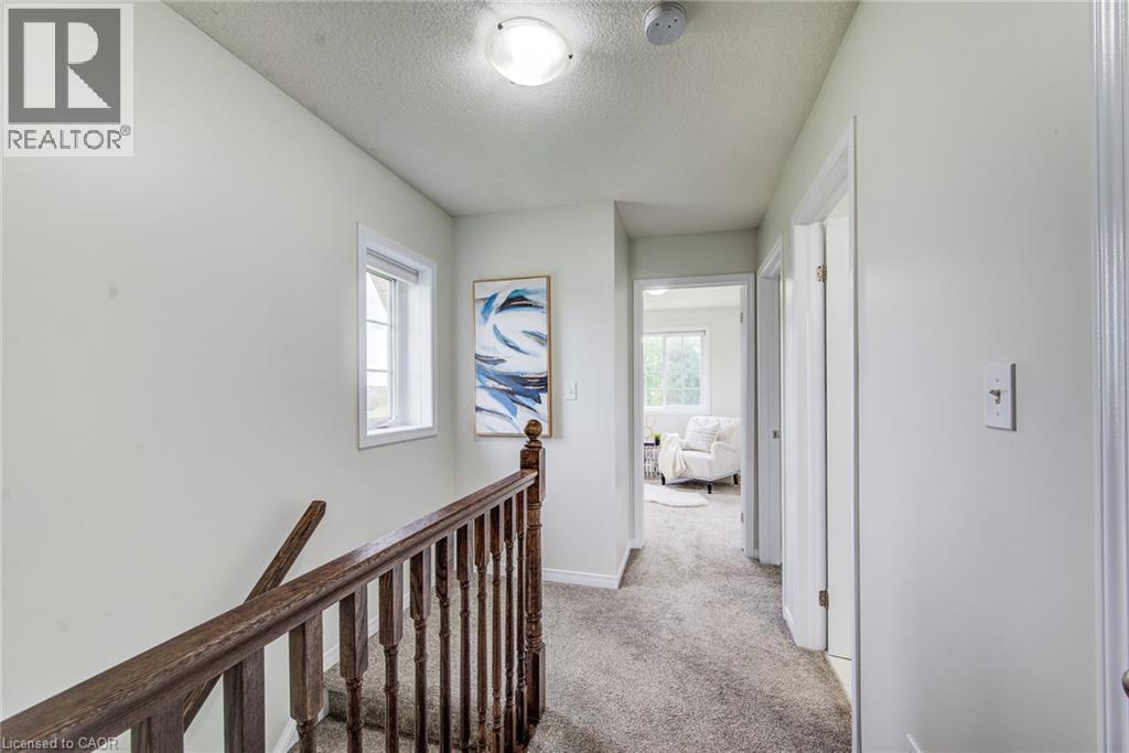 Upper hallway with carpeting, natural wood banister, and a white-framed window - 226 Maitland Street, Kitchener, ON