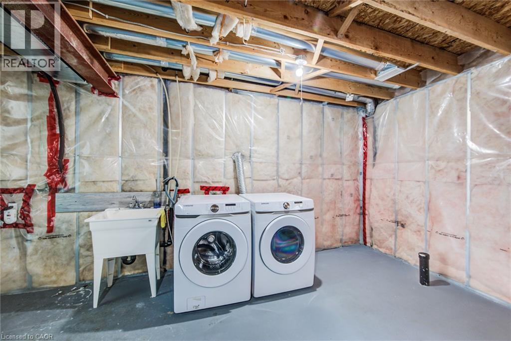Unfinished basement area featuring exposed ceiling joists, insulated walls, a utility sink, and a painted concrete floor - 226 Maitland Street, Kitchener, ON
