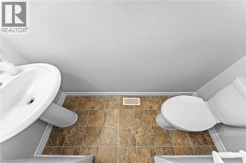 Pedestal sink with white basin, white toilet, and tile flooring - 245 Red Clover Court, Kitchener, ON