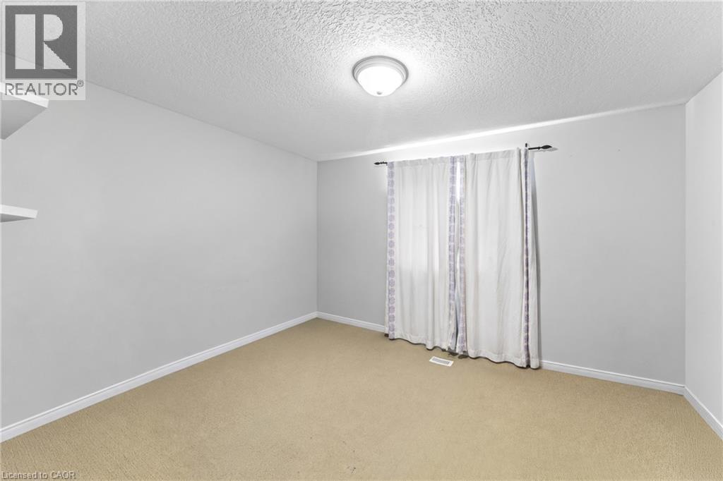 Neutral wall paint, textured ceiling, flush mount ceiling light, and carpeted flooring - 245 Red Clover Court, Kitchener, ON