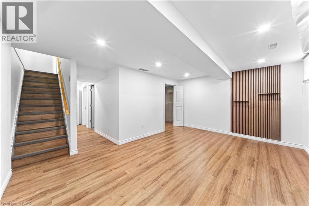 Recessed lighting, wood-finish flooring, wood slatted accent wall with integrated shelving, white walls, wood staircase - 245 Red Clover Court, Kitchener, ON