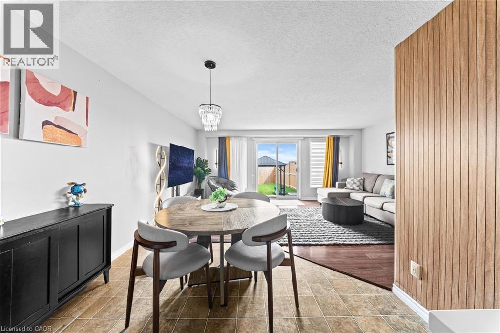 Open living space featuring wood-finish flooring, light-toned wall paneling, and sliding glass doors - 245 Red Clover Court, Kitchener, ON