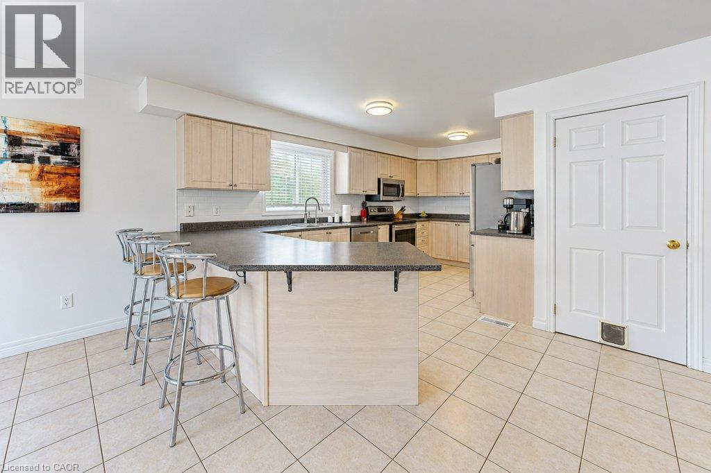 Kitchen featuring light wood-finish cabinetry, solid surface countertops, stainless steel appliances, and tiled flooring - 88 Decaro Crescent, Cambridge, ON