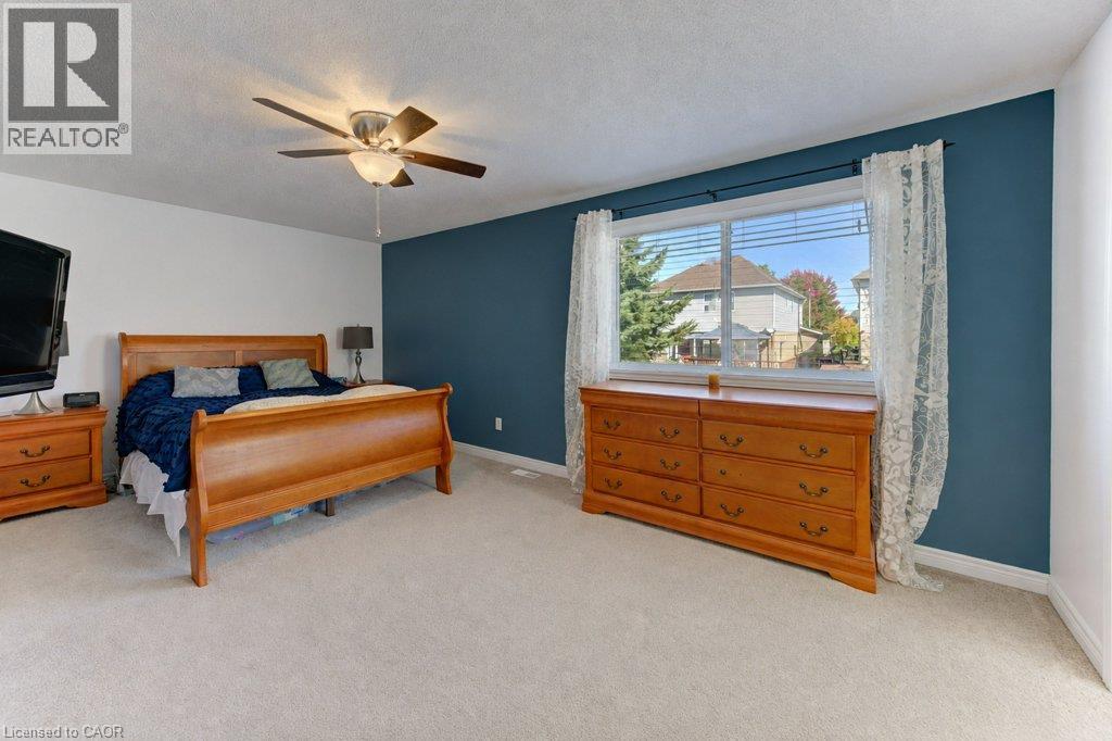 Carpeted flooring, a ceiling fan with integrated lighting, and a large window with blinds - 88 Decaro Crescent, Cambridge, ON