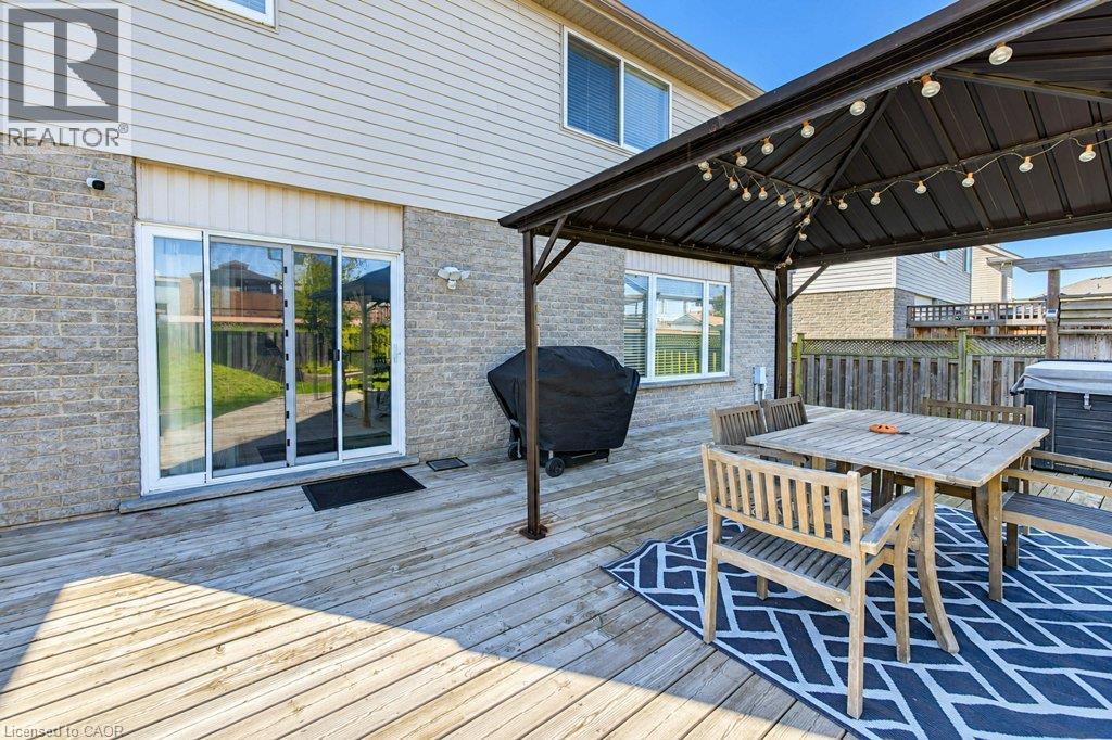 Expansive decking with integrated outdoor dining area beneath a pergola-style shade structure - 88 Decaro Crescent, Cambridge, ON