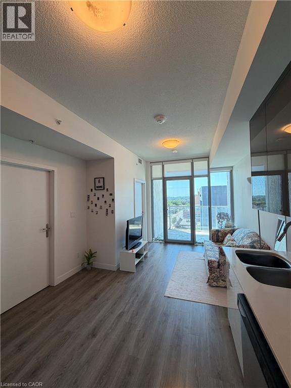Open-concept living area with wood-finish flooring, recessed lighting, and a glass sliding door leading to an outdoor space - 60 Frederick Street Unit# 1213, Kitchener, ON