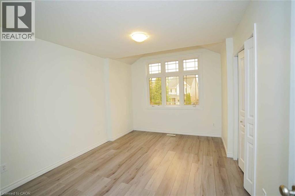 Wood-finish flooring, bay window with multiple panes, ceiling-mounted light fixture, and bifold closet doors - 18 Heritage Drive, Guelph, ON