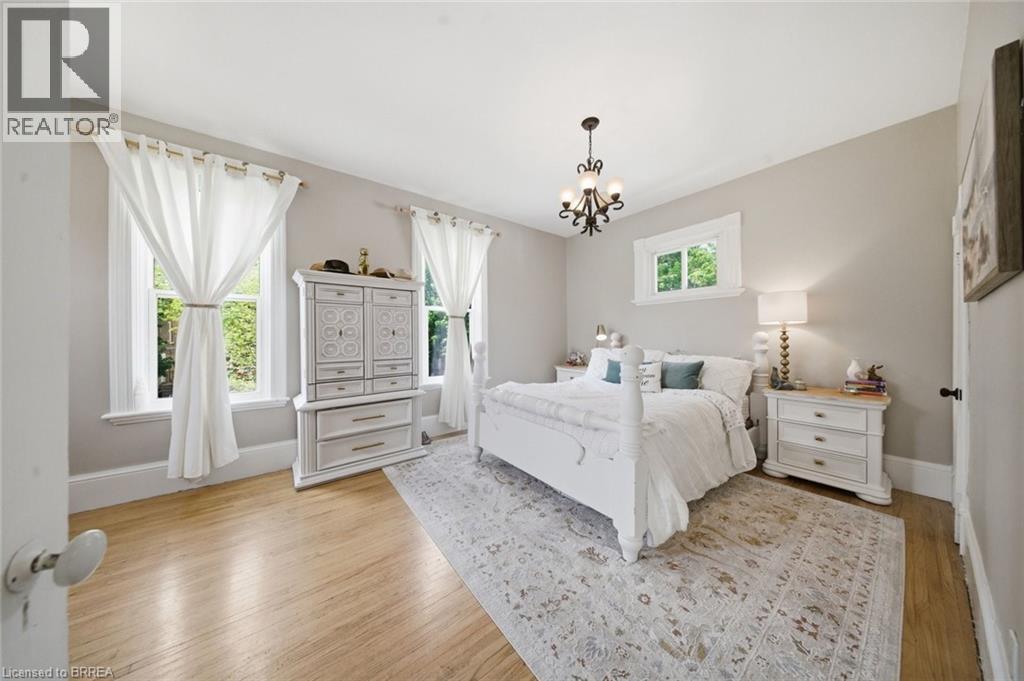 Well-lit room featuring wood-finish flooring, light gray walls, white trim, and a decorative chandelier - 62 East Avenue, Brantford, ON