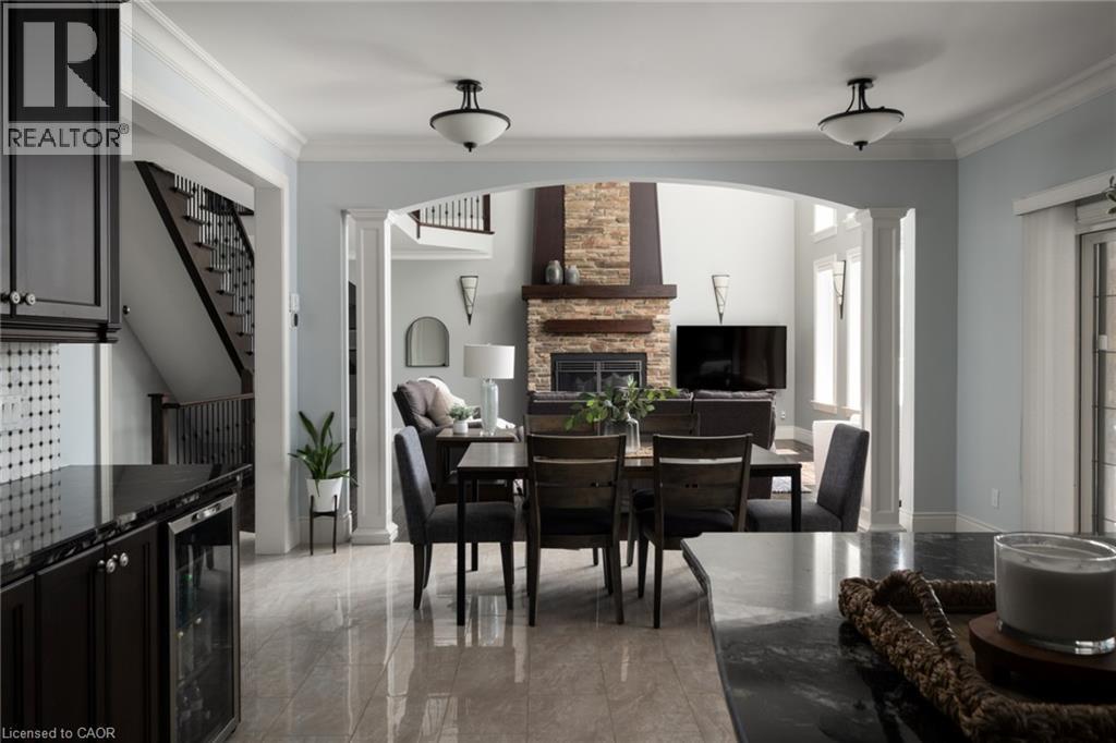 Arched entryway with column detailing, stone-accented fireplace, wood-finish mantel, and tiled flooring - 1505 Milburough Line, Carlisle, ON