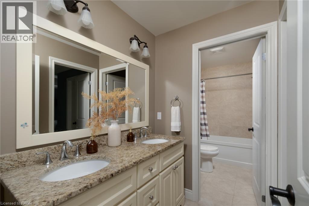 Dual vanity with integrated sinks, granite-finish countertop, and decorative wall-mounted light fixtures - 1505 Milburough Line, Carlisle, ON